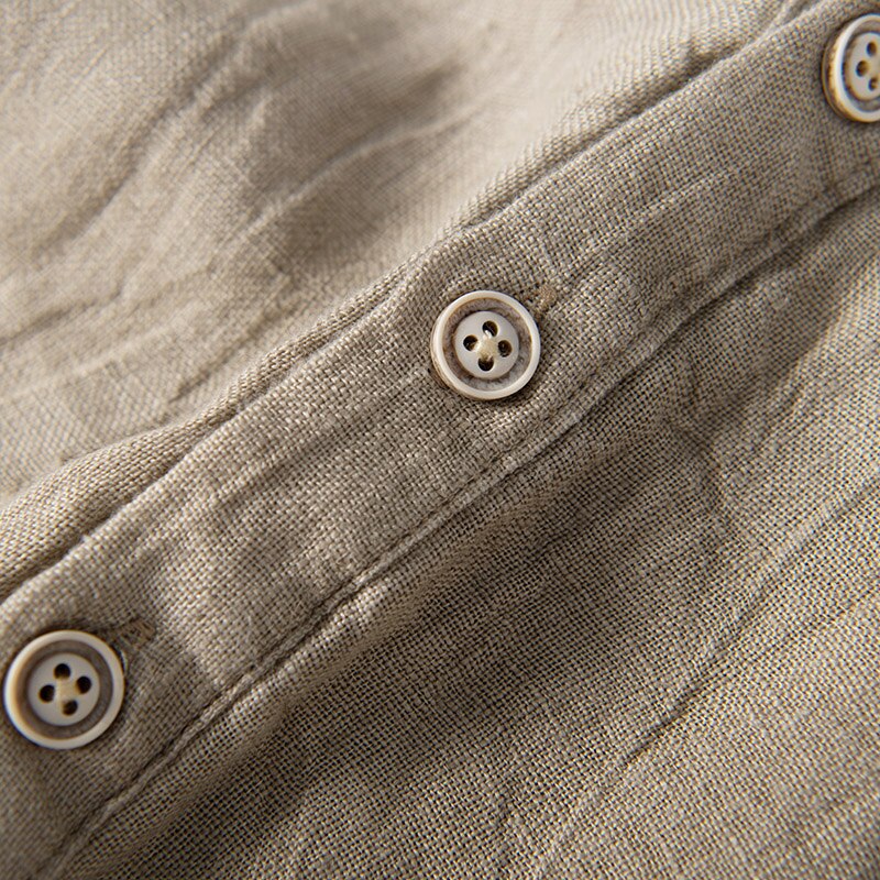 Button detail of Natural colour Shirt with relaxed fit and short sleeves  with Round stand-up collar V-neck front opening .